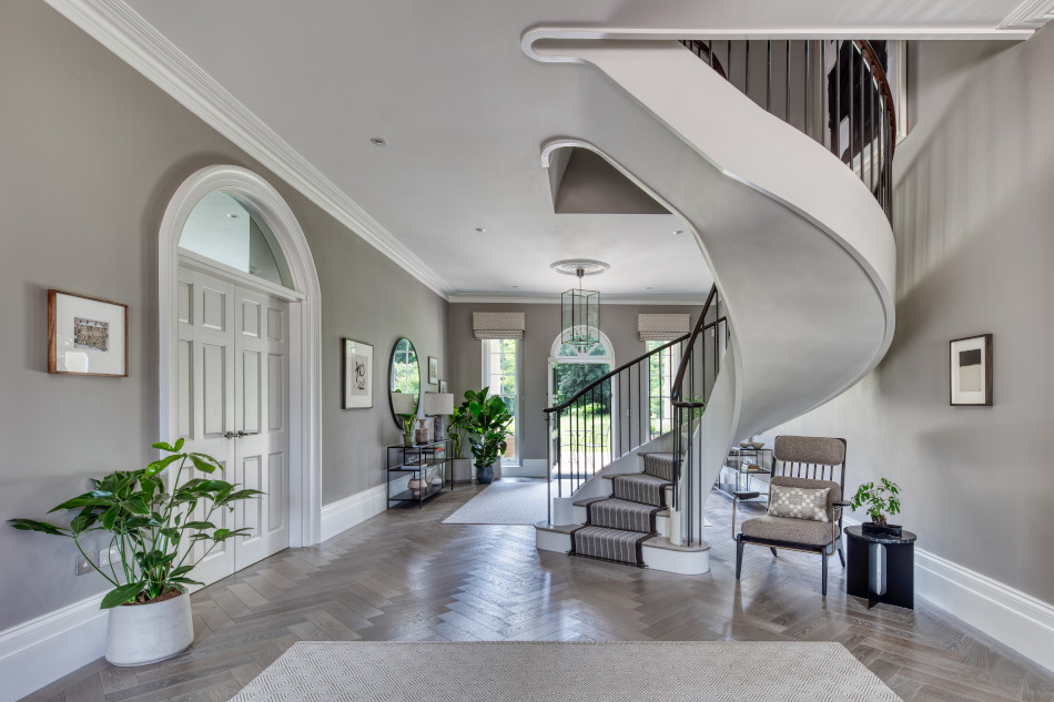 A wide shot of a large contemporary hallway in a historic house showcasing a beautiful herringbone floor.