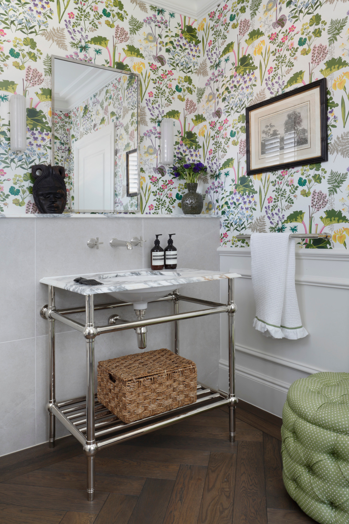 A traditional bathroom in the West Sussex House interior design project showing a marble and metal basin, mirror, towel and brightly coloured floral wallpaper.