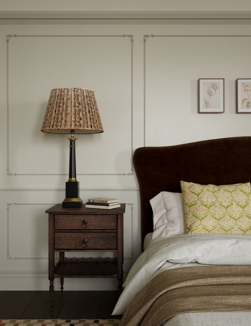 A elegant wall panelled master bedroom shows a luxurious double bed alongside dark wood bedside table. On top is a large candlestick table lamp complete with floral lampshade. Used for the Lighting Design section of Studio Hooton's interior design services.
