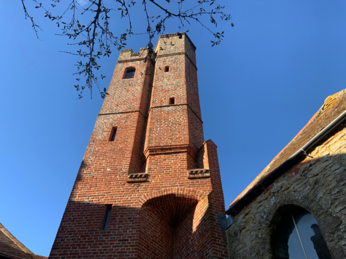 Large red brick built tower in front of a deep blue sky, part of the 15th Century Manor House project at Studio Hooton