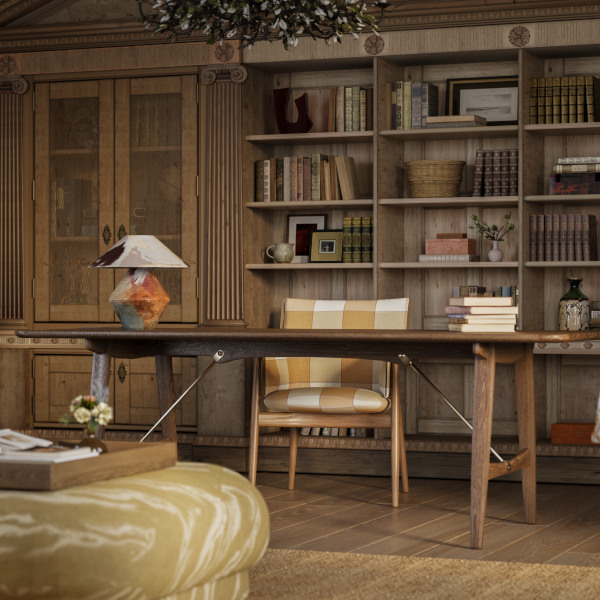 A large dark wood modern Scandanavian desk with books and table lamp sits in front of a wooden upholstered armchair which in turn sits in front of floor to ceiling dark wood shelves and cabinets which from the library of the Sussex estate.