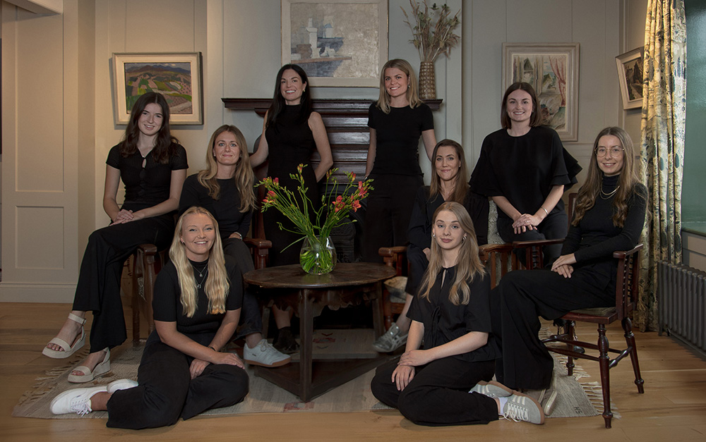 Studio Hooton Team - 9 members of the Studio Hooton team dressed in black clothing sat for a group portrait photo in an elegantly designed period room.